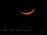 A Crescent Moon Dwarfs the Lights of Fort Riley Army Base in Central Kansas, January 22, 2007 Photographic Print by Charlie Riedel