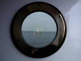 A Porthole Provides a Brass Frame for a Passing Sailboat Photographic Print by Stephen St. John