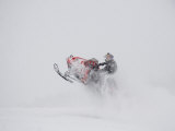 A Snowmobiler Jumps from a Hill on a Snowy Day Impressão fotográfica por Taylor S. Kennedy