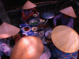 Women in Traditional Conical Hats Sitting Down to Meal at Market, Hoi An, Vietnam Photographic Print by John Banagan