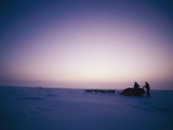 Huskies Carry a Sled Across the Ice at Twilight Photographic Print by Gordon Wiltsie