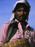 An Indian Snake Charmer Holds a Basket with a King Cobra in It Photographie par Ed George