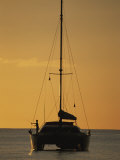 A Fisherman and His Sailboat are Silhouetted against the Yellow Sky Photographic Print by Michael Melford