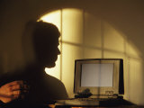 The Shadow of a Man is Projected onto a Wall as He Uses a Computer Photographic Print by Joel Sartore