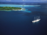 A Masted Boat Lies at Anchor off of a Pacific Island Photographic Print