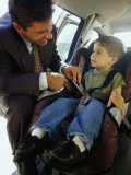 Mid Adult Man Strapping His Son into a Car Fotografie-Druck