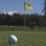 Golf Ball on the Lawn in Front of a Flag Photographic Print