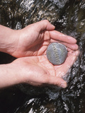 Person Holding Rock with the Word Blessings in Rushing Water Fotografie-Druck