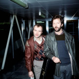 Phil Collins with Eric Clapton Leaving London Airport for Barbados, March 1984 Fotografisk tryk Phil Collins with Eric Clapton Leaving London Airport for Barbados, March 1984 Fotografisk tryk
