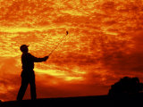 Man Swinging Golf Club at Sunset Photographie par Bill Bachmann