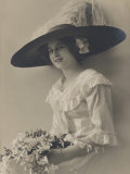 An Attractive Young Woman Wearing a Wide-Brimmed Hat Posing with a Bouquet of Flowers Photographie