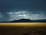 The Setting Sun Permeates Rain Clouds to Brighten Black Rock Desert, Nevada Photographie par James P. Blair
