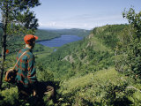 Hiker Looks Down on a Lake Surrounded by Mountains Fotografisk trykk av Andrew Brown Hiker Looks Down on a Lake Surrounded by Mountains Fotografisk trykk av Andrew Brown