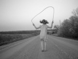 A Girl Jumps Rope Down a Gravel Road in Nebraska Photographic Print by Joel Sartore