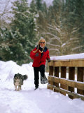 Joy Tessman, with her canine companion by her side, is snowshoeing in the hills Photographie