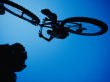 A mountain biker careens in the air and the photographer captures this dynamic image from beneath Lámina fotográfica A mountain biker careens in the air and the photographer captures this dynamic image from beneath Lámina fotográfica