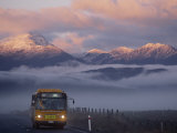 Bus au soleil levant avec les montagnes enveloppées dans le brouillard Photographie