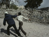 A Policeman Grabs the Collar of a Young Man Near a Stone Wall Photographie