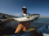 A Fisherman Holds a Large Fish Before Placing it in a Boat Photographie