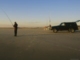 A Man Holds a Fishing Pole While Standing Near His Jeep Truck Photographic Print by Stephen Alvarez