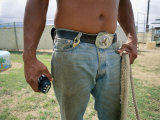 A Close View of a Man in Jeans with a Large Belt Buckle Holding a Rope Photographic Print by Jodi Cobb
