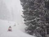 A Small Group of Snowmobilers Turn a Corner in a Snowstorm Photographic Print by Taylor S. Kennedy