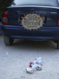 A "Just Married" Sign and Tin Cans are Atached to the Back of a Car Photographie par Stephen Alvarez