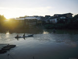 The Sun Sets Behind Waterfront Housing as People Paddle a Canoe Back Home Photographic Print by Steve Raymer