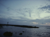 A Silhouetted Person Walks Down a Jetty at Twilight Photographic Print by Sam Kittner