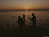 Several People are Silhouetted Standing in Shallow Water at Sunset Photographic Print by Sam Kittner