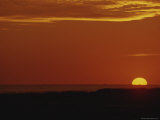 The Sun Sets Behind the Water in an Orange Sky Photographie