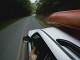 A Car with a Kayak on Top Speeds Down a Two-Lane Highway Photographic Print