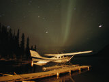 The Aurora Borealis Glows Brightly over a Seaplane Docked on Cli Lake Photographie par Raymond Gehman