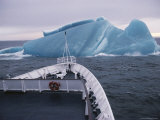 A ship approaching an unusual deep blue iceberg in Antarctic Sound. Lámina fotográfica