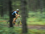Panned View of a Cyclist Riding Along a Path Through Woods Photographic Print by Mark Cosslett