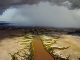 An Aerial View of a Coffee-Colored River with Rain in Distance Photographic Print by Randy Olson