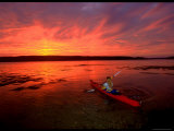 A Woman Paddles a Sea Kayak at Dusk Photographic Print