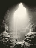 A Man Stands in Front of a Skylit Cave Waterfall Photographic Print