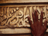 A Man Runs His Hand Over Arabic Script at the Famous Jama Masjid Fotografie-Druck von Justin Guariglia