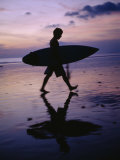 A Surfer Walks Along Kuta Beach at Dusk with His Surfboard in Hand Photographic Print by Justin Guariglia