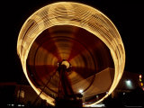 A Time Exposure Blurs the Spin of a Bright Carnival Ride Photographic Print by Stephen St. John