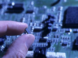Fingers Hold up a Chip from a Computer Board Photographic Print by Taylor S. Kennedy