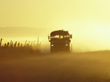 Rural School Bus Driving Along Dusty Country Road, Oregon, USA Photographic Print by William Sutton