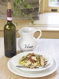 Bottle and Pitcher of Wine Beside Bowl of Pasta Lámina fotográfica