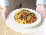 Person Serving Bowl of Pasta with Grilled Vegetable Sauce Fotografisk tryk Person Serving Bowl of Pasta with Grilled Vegetable Sauce Fotografisk tryk