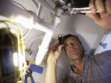 Low Angle View of a Young Man Checking the Plumbing with a Flashlight Lámina fotográfica Low Angle View of a Young Man Checking the Plumbing with a Flashlight Lámina fotográfica