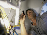 Low Angle View of a Young Man Checking the Plumbing with a Flashlight Fotografická reprodukce