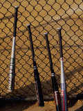 Baseball Bats Resting Against a Chain-Link Fence Photographic Print