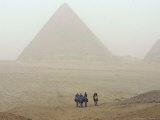 Tourists Ride Camels Through a Dust Storm at the Site of the Great Pyramids Lámina fotográfica Tourists Ride Camels Through a Dust Storm at the Site of the Great Pyramids Lámina fotográfica