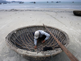 A Vietnamese Fisherman Does Repairs on His Basket Boat on a Beach Fotografie-Druck